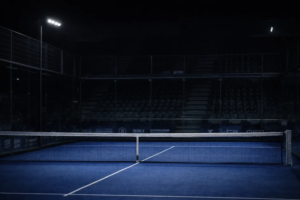 Red de una pista de pádel vacía en un torneo menor con gradas vacías y ambiente sombrío